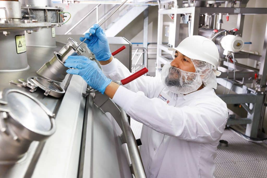 Corporate lifestyle photography of a technician working in protective gear inside a food processing facility