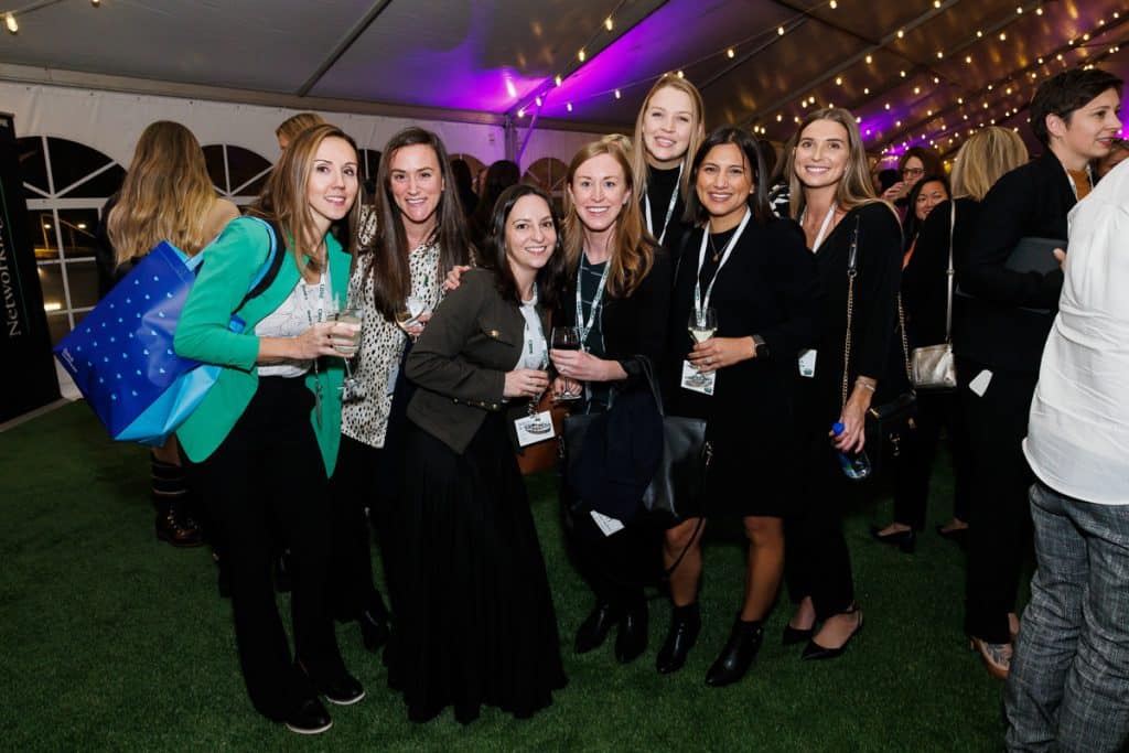 Chicago corporate event photographer captures professional women networking at corporate cocktail event with drinks, name badges, and festive lighting