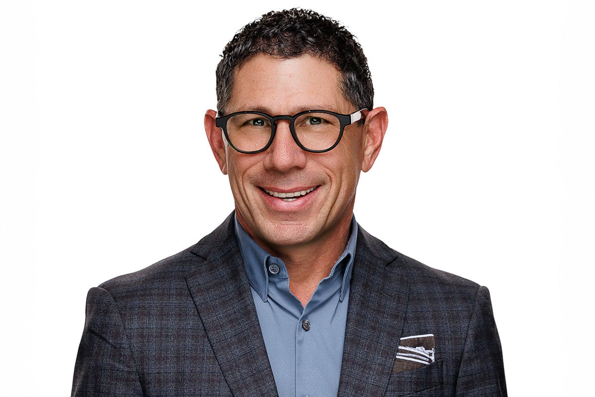 Smiling man wearing glasses and a checked jacket, professional Chicago corporate headshot.