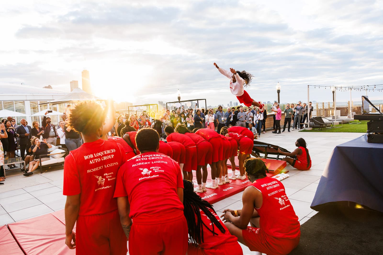 The Jesse White Tumblers performing for guests during a corporate rooftop reception as attendees watch the live entertainment.