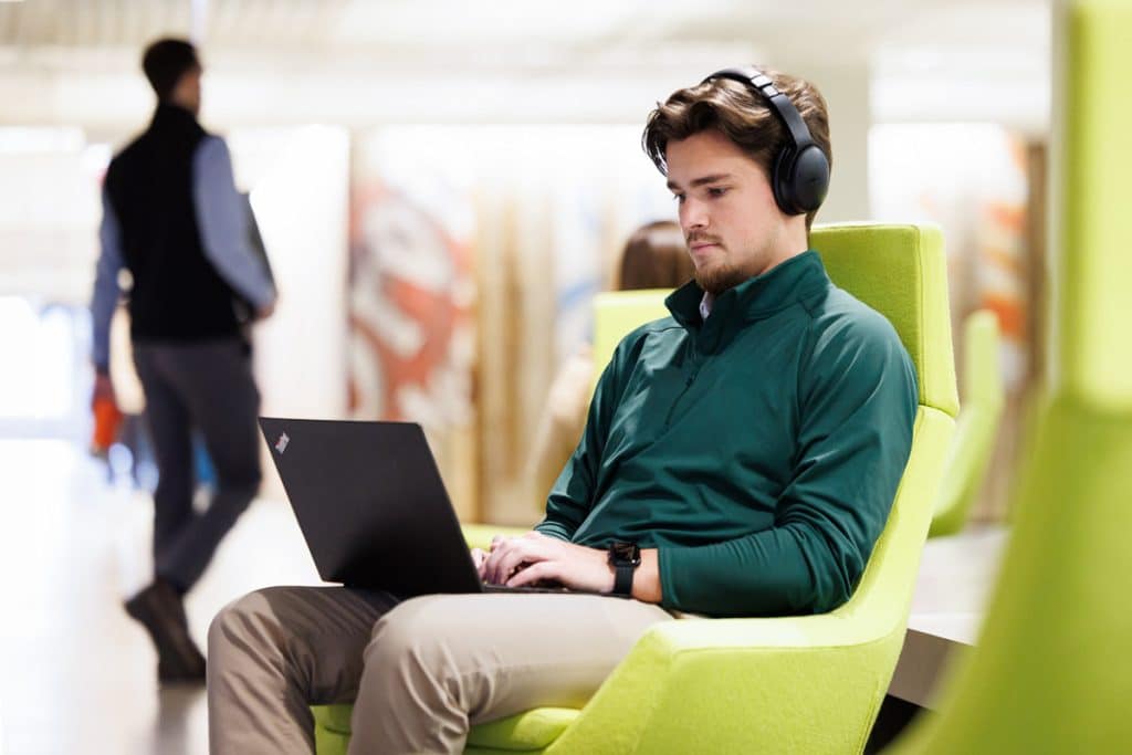 Young professional wearing headphones works remotely on a laptop in a stylish Chicago business lounge