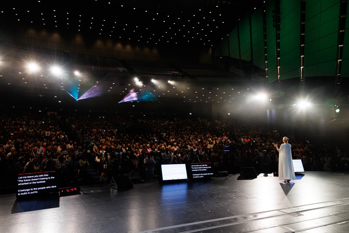 Behind-the-stage view of a keynote speaker addressing a large audience in a packed auditorium, photographed by a Chicago corporate event photographer.