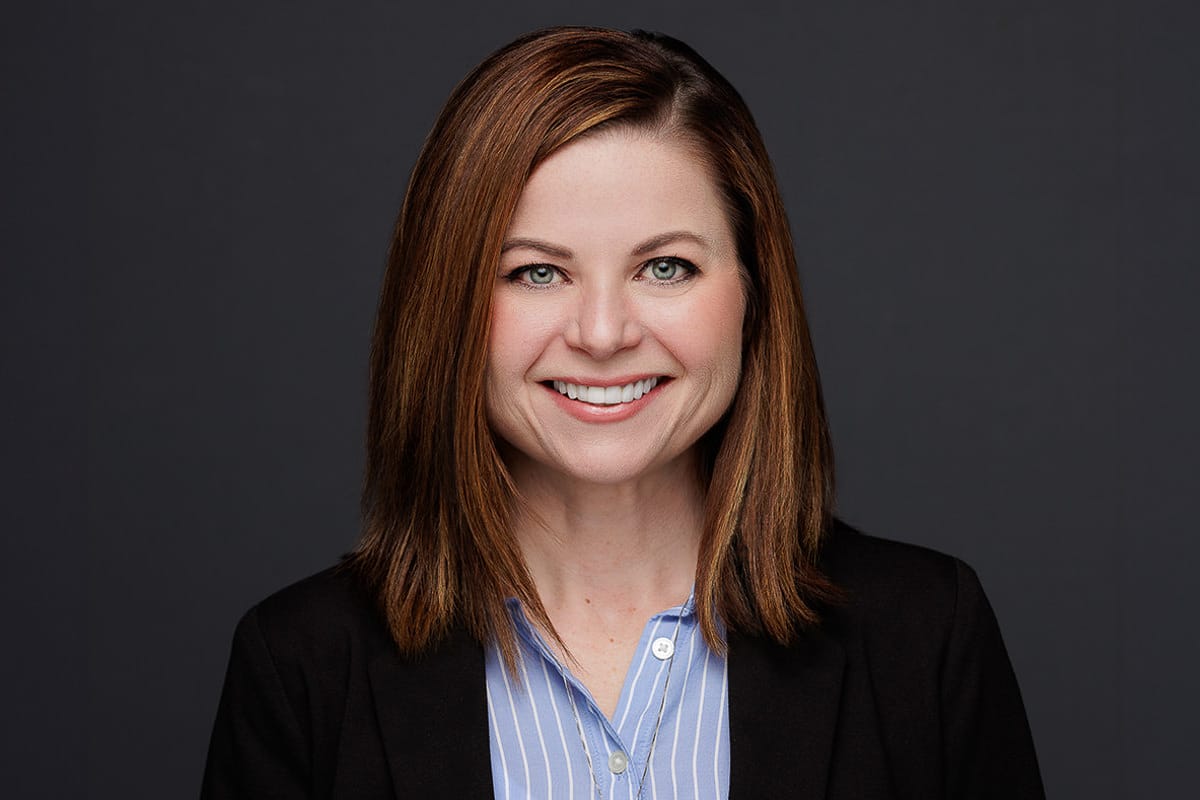Smiling woman in a black blazer and striped shirt, professional Chicago corporate headshot.