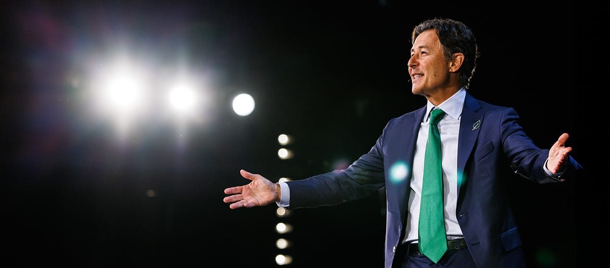 Keynote speaker on a brightly lit main stage with strong backlighting, photographed by a Chicago corporate event photographer.