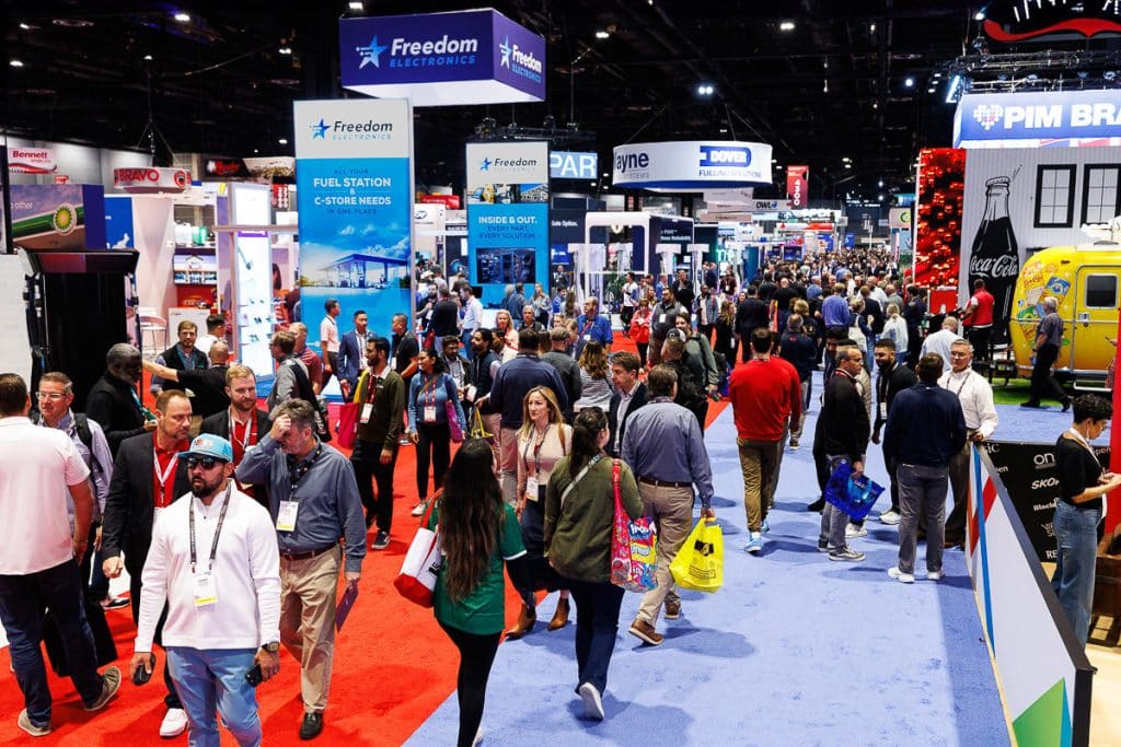 Wide view of attendees walking the trade show expo floor during a corporate conference.